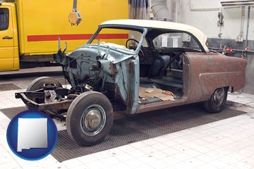 a vintage automobile in an auto body shop - with New Mexico icon